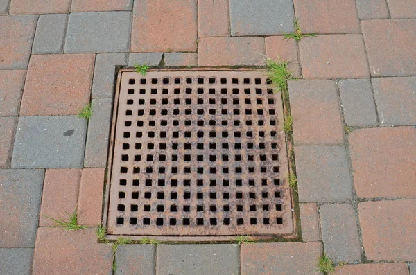 Metal drain or grate with rectangle stone tiles — Stock Photo, Image