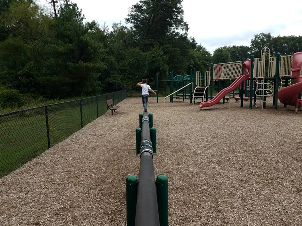 Garçon enfant sur balancier faisceau sur aire de jeux — Photo