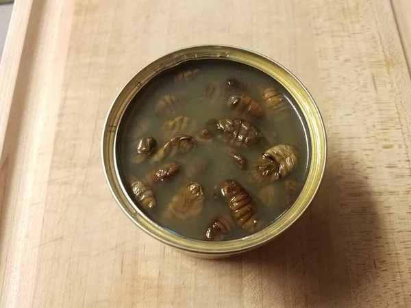 Larva de inseto marrom em lata na placa de corte de madeira — Fotografia de Stock