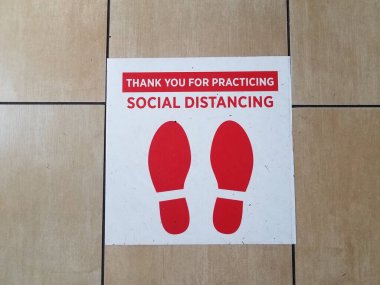 beyaz ve kırmızı sosyal uzaklık işareti ve yerde ayakkabılar