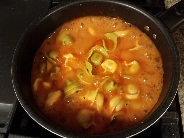 토르텔리니 파스타와 토마토 소스 수프를 냄비에 넣고 — 스톡 사진