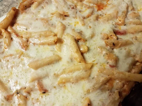 Cheesy penne pasta in glass baking dish — Stock Photo, Image