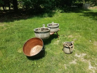 Su dolu ahşap kovalar ve yeşil çimenli bakır bir tava.