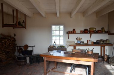 Rafları, tencereleri, kapları, yakacak odunları ve pencereleri olan ahşap masa.