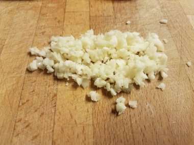 Ağaç kesme tahtası ve beyaz sarımsak parçaları.