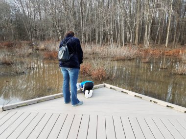 Kadın ve çocuk iskelede sulak arazide ya da bataklıkta suya bakıyorlar.