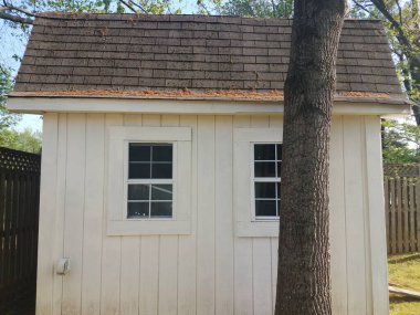 Çatıda polenler olan küçük beyaz ahşap bir kulübe.