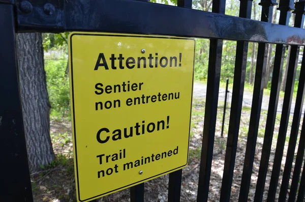 黄色の警戒歩道はフェンスの上に英語とフランス語で標識を維持していません — ストック写真