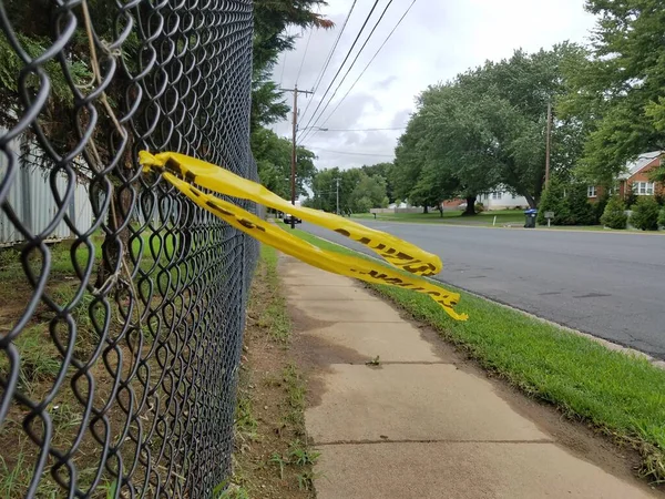 チェーンリンクフェンスと歩道と道路上の黄色の警戒テープ — ストック写真