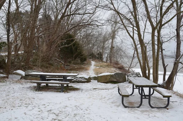 wood picnic tables with trail or path and snow along Potomac river