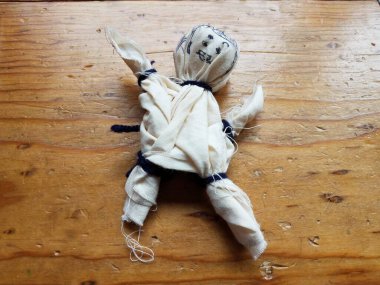 Kahverengi tahta zeminde beyaz doldurulmuş bez bebek.