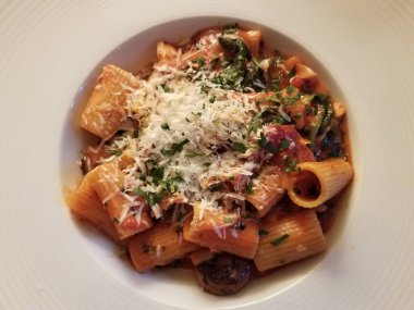 Beyaz kasede sebzeli ve peynirli İtalyan makarnası.