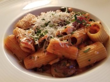 Beyaz kasede sebzeli ve peynirli İtalyan makarnası.