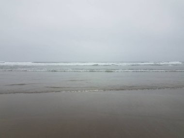 Sahilde ya da sahilde Okyanus dalgaları ve kumla