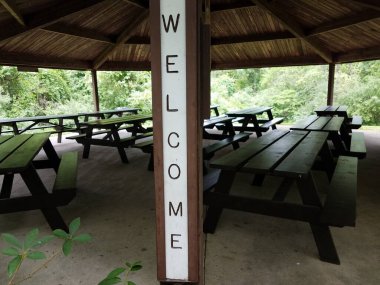 Piknik köşküne hoş geldin tabelası ve park masaları.