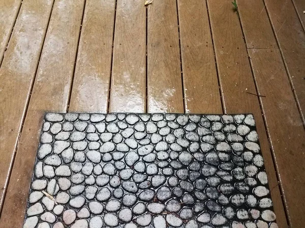 雨と歓迎マットの間に水と複合材の木製デッキ — ストック写真