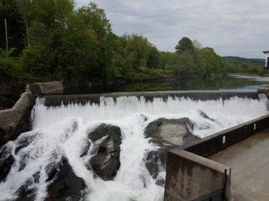 Şelale veya akarsular ve kayalar ve ağaçlar ve bina