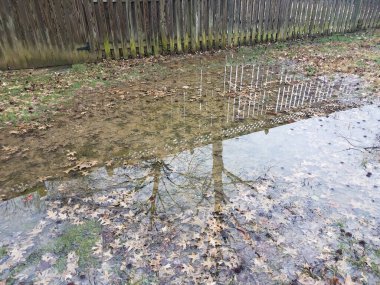 Yansıma ve ahşap çitlerle dolu büyük su birikintisi.