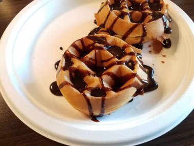 Beyaz tabakta waffle üzerine çikolata şurubu.