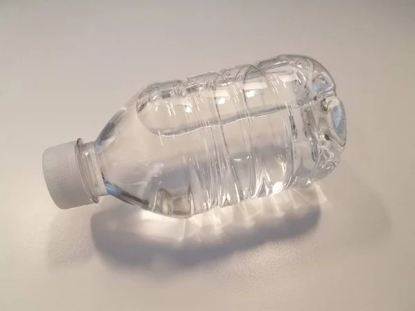 Маленькая Пластиковая Бутылка Водой Белой Поверхности — стоковое фото