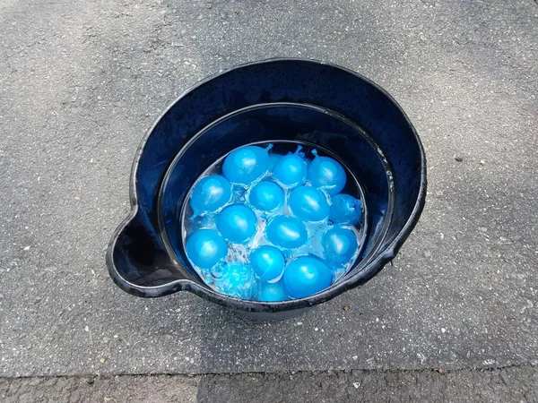 Ein Schwarzer Plastikeimer Mit Blauen Wasserballons Auf Asphalt — Stockfoto