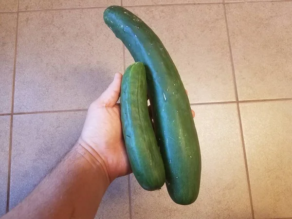 Een Hand Met Groene Komkommers Een Tegelvloer — Stockfoto