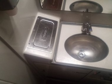 Banyodaki metal lavabo ve çöp tenekesi ya da trendeki tuvalet.