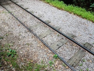 Tren rayları, küçük taşlar ve yeşil çimenler.