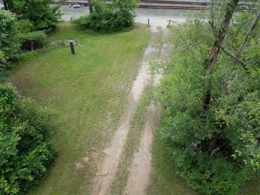 Toprak yol ve yeşil çimen ve ağaçlar yukarıdan ve demiryolu raylarından