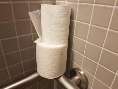banyo duvarında ve tuvalet kağıdında bir sürü kare gri kiremit var.