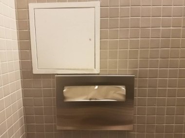 Klozet kapağı koruyucusu ve banyo duvarında küçük bir kapı.