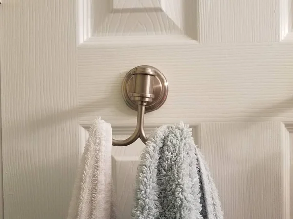 浴室或卫生间白色门上的金属毛巾衣架 — 图库照片