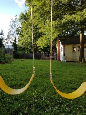 Arka bahçedeki sarı salıncaklar oyun yapıları ve yeşil çimenler