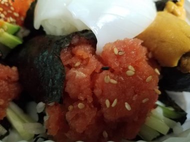 Bir tabak dolusu suşi, ton balığı, somon balığı ve pirinç gibi.