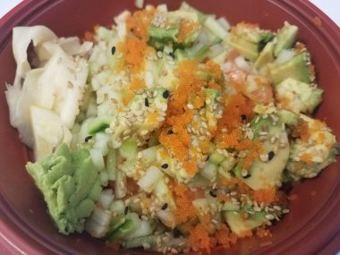 İçinde balık, balık yumurtası, avokado ve pirinç olan kırmızı bir kase.