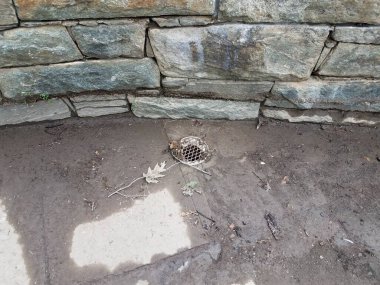 Metal drenajı ve çamuru olan gri taş duvar