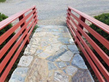 Taştan bir patika ya da kırmızı ahşap korkuluklu bir patika.
