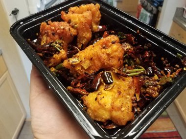 Mutfakta biberli baharatlı Çin yemeği dolu siyah plastik bir konteynır.