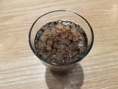 Bir bardak soda ya da kahverengi ahşap masada buzlu meşrubat.