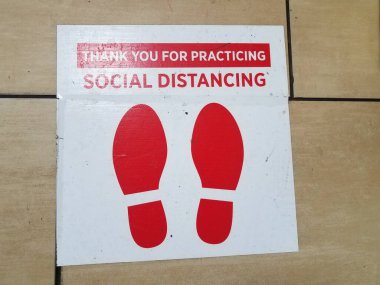 Beyaz ve kırmızı sosyal uzaklık işareti ve yerde kırmızı ayakkabılar.