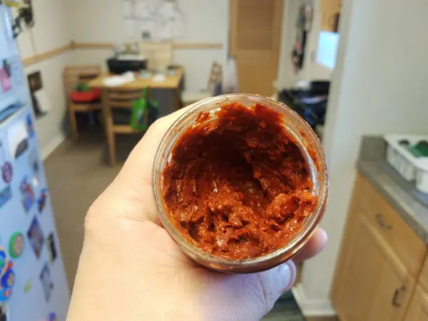 Hand Hålla Behållare Med Kryddig Röd Sås Med Röd Paprika — Stockfoto