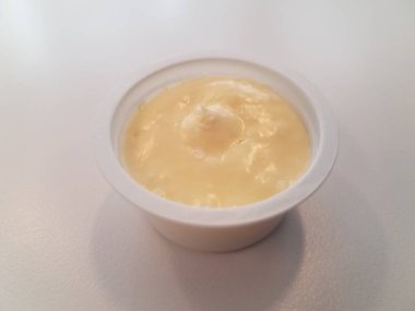 Beyaz bir yüzey üzerinde sarı tereyağlı küçük plastik bir kontanatör.