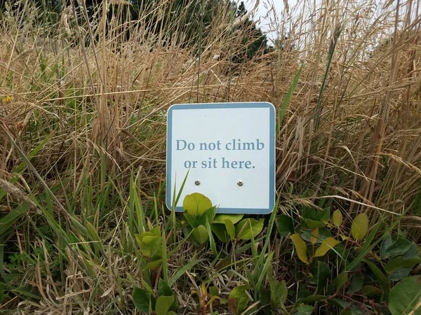 不要爬或坐在这里 在褐色和绿色的草丛中签名 — 图库照片
