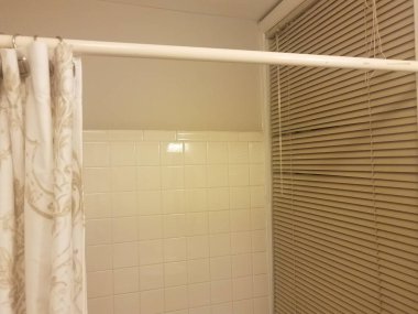 Banyoda ya da tuvalette beyaz fayanslı duş ve panjurlu pencere.