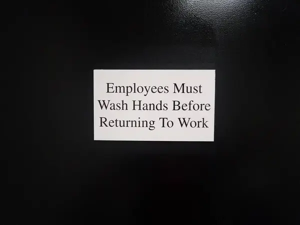 白い従業員は黒いドアや壁の標識に戻る前に手を洗う必要があります — ストック写真