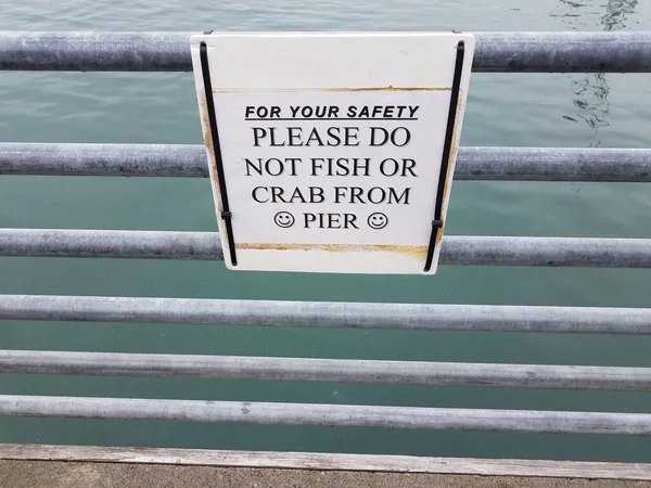 为了您的安全起见 请不要在带有水的金属栏杆上的码头标志上钓鱼或蟹 — 图库照片