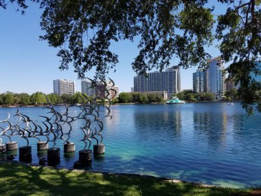 Göl kenarındaki binalarla uçan kuşların metal heykeli