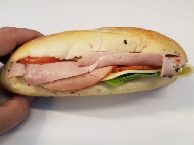 Beyaz masa ya da yüzey üzerinde domatesli, ekmekli ve salamlı sandviç.