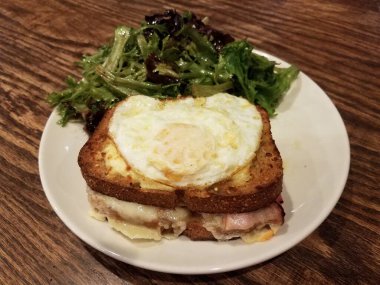 Jambonlu sandviç, erimiş peynir ve tabakta salata.