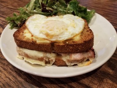 Jambonlu sandviç, erimiş peynir ve tabakta salata.